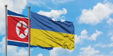 North Korea and Ukraine flag waving in the wind against white cloudy blue sky together. Diplomacy concept, international relations.