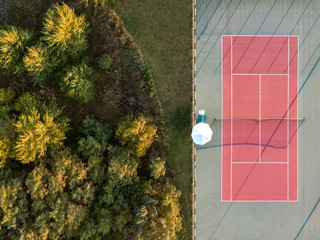 aerial top down shot of tennis court with trees on the other side. 