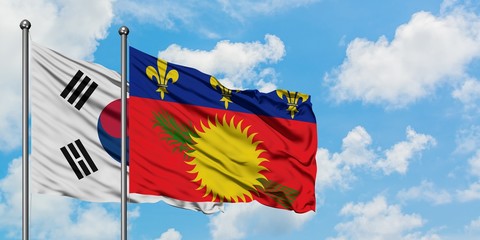 South Korea and Guadeloupe flag waving in the wind against white cloudy blue sky together. Diplomacy concept, international relations.