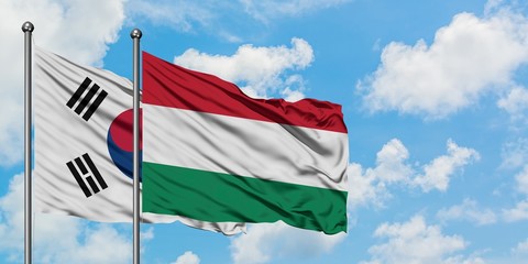 South Korea and Hungary flag waving in the wind against white cloudy blue sky together. Diplomacy concept, international relations.