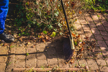 Cleaning in the garden. The concept of care for cleanliness and order in the garden. The man cleans the leaves, old branches throwing them into the bag. Sweeping dust and leaves.