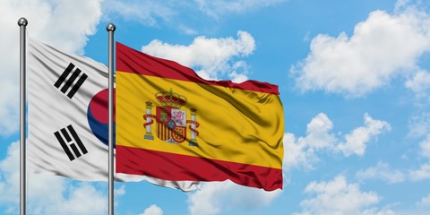 South Korea and Spain flag waving in the wind against white cloudy blue sky together. Diplomacy concept, international relations.