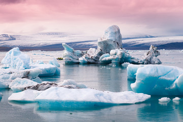 Jokulsarlon glacier lagoon in Iceland. Blue icebergs and tour boat on lake water. Northern nature...