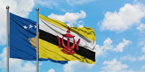 Kosovo and Brunei flag waving in the wind against white cloudy blue sky together. Diplomacy concept, international relations.