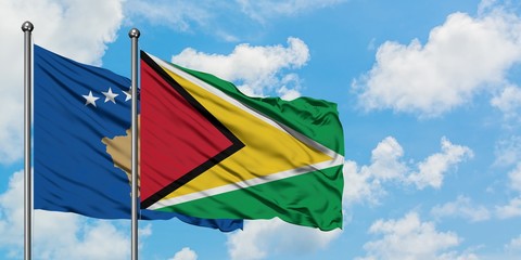 Kosovo and Guyana flag waving in the wind against white cloudy blue sky together. Diplomacy concept, international relations.