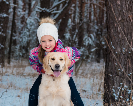 Cute girl portrait embrace with her dog golden retriever in winter park walking. Friendship, pet and human. woman playing with dog outdoors