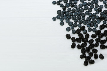 Blueberries and blackberries,blueberries on white wooden background. Healthy food. Place for label