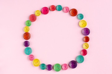 Colored sewing buttons composition on pink background.