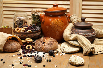 Fototapeta na wymiar fresh bread, bagels, dried fruits, seeds, salt, jar and wheat on the wooden - still life and healthy eating concept