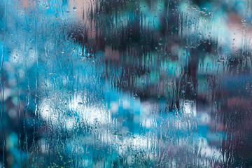 Wet glass with abstract light blue blurs