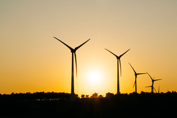 Renewable energy wind turbines on the mountain at sunset time