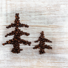 Shape of Christmas tree made of coffee beans, anise star and cinnamon sticks, on wooden table. Winter holidays concept. Top view, copy space. Wooden, natural background