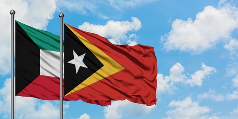 Kuwait and East Timor flag waving in the wind against white cloudy blue sky together. Diplomacy concept, international relations.