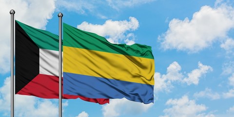 Kuwait and Gabon flag waving in the wind against white cloudy blue sky together. Diplomacy concept, international relations.