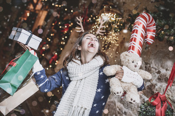 Woman laughing with many christmas gifts and teddy bears in the shopping passage