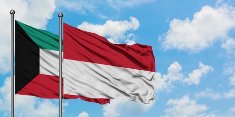 Kuwait and Indonesia flag waving in the wind against white cloudy blue sky together. Diplomacy concept, international relations.