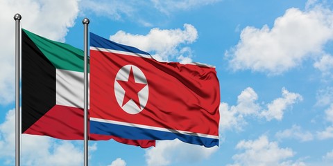 Kuwait and North Korea flag waving in the wind against white cloudy blue sky together. Diplomacy concept, international relations.