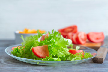 Leaf lettuce salad with tomatoes on a glass plate.