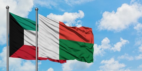 Kuwait and Madagascar flag waving in the wind against white cloudy blue sky together. Diplomacy concept, international relations.