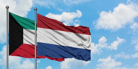 Kuwait and Netherlands flag waving in the wind against white cloudy blue sky together. Diplomacy concept, international relations.