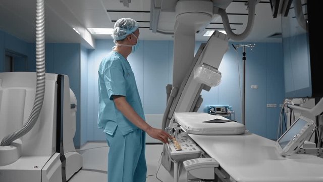 Cardiac surgeon prepares to medical 3d diagnostic procedure via robotic magnetic navigation system. Operating room, hospital, indoor