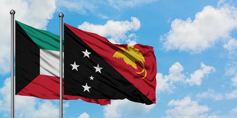 Kuwait and Papua New Guinea flag waving in the wind against white cloudy blue sky together. Diplomacy concept, international relations.