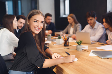 Smiling businesswoman with colleagues working on background