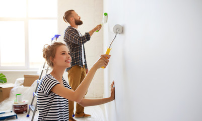 young happy couple is repairing and painting wall at home