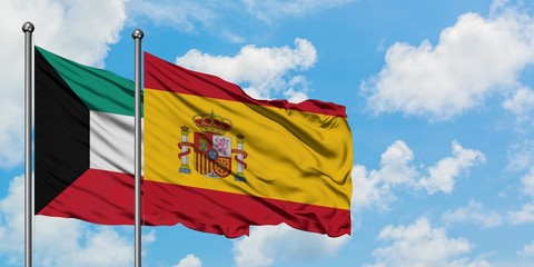 Kuwait and Spain flag waving in the wind against white cloudy blue sky together. Diplomacy concept, international relations.