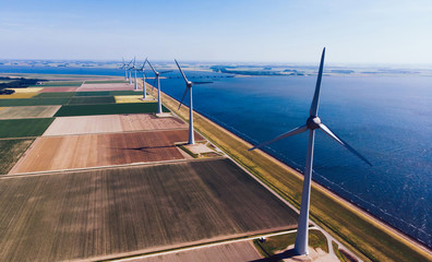 Huge modern windmills with turbines powered with wind power providing ecological energy on rural environment during summer day. Line of turbines producing electricity
