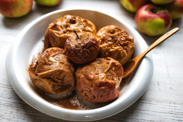 Baked apples, sprinkled with cinnamon and honey in a ceramic dish