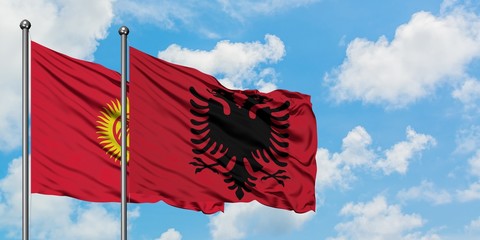 Kyrgyzstan and Albania flag waving in the wind against white cloudy blue sky together. Diplomacy concept, international relations.