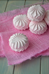 Delicate pink marshmallow or zephyr on pink napkin and teal background. Vertical image