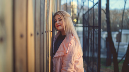 A portrait of a beautiful girl, posing near a wooden fence at sunset in springtime.