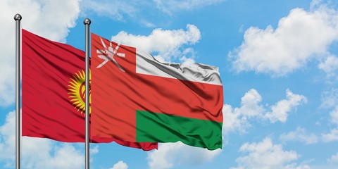 Kyrgyzstan and Oman flag waving in the wind against white cloudy blue sky together. Diplomacy concept, international relations.