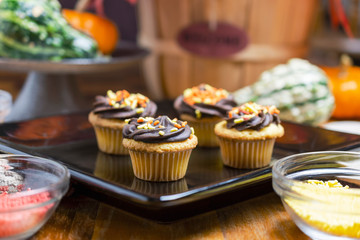 Autumn themed mini cupcakes.  Yellow cake with chocolate frosting with orange, red, and yellow sprinkles.  Cupcakes on black square plate.