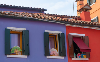 Windows with fans in blue and red wall of the houses. Background, travel photo.