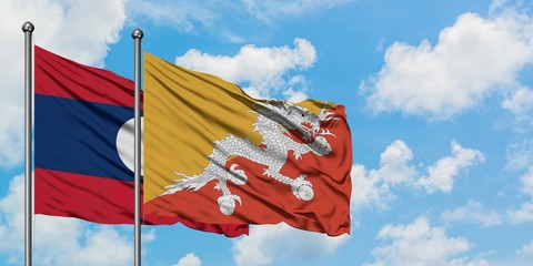 Laos and Bhutan flag waving in the wind against white cloudy blue sky together. Diplomacy concept, international relations.