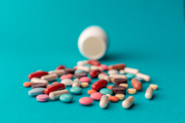 A handful of colored pills spilled out of the can on a blue background. Medical concept
