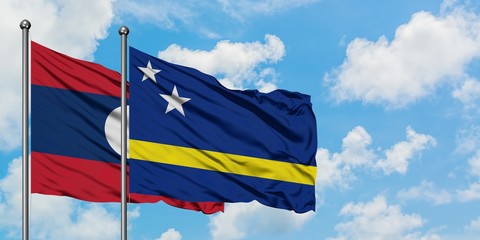 Laos and Curacao flag waving in the wind against white cloudy blue sky together. Diplomacy concept, international relations.