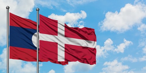 Laos and Denmark flag waving in the wind against white cloudy blue sky together. Diplomacy concept, international relations.