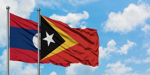 Laos and East Timor flag waving in the wind against white cloudy blue sky together. Diplomacy concept, international relations.
