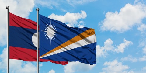 Laos and Marshall Islands flag waving in the wind against white cloudy blue sky together. Diplomacy concept, international relations.