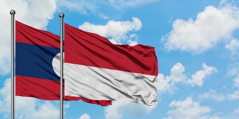Laos and Monaco flag waving in the wind against white cloudy blue sky together. Diplomacy concept, international relations.