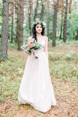 Obraz na płótnie Canvas Bride holding wedding bouquet in rustic style on a background of pine forest