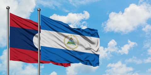 Laos and Nicaragua flag waving in the wind against white cloudy blue sky together. Diplomacy concept, international relations.
