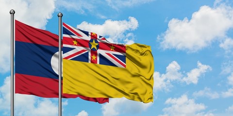 Laos and Niue flag waving in the wind against white cloudy blue sky together. Diplomacy concept, international relations.