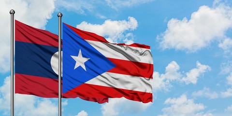 Laos and Puerto Rico flag waving in the wind against white cloudy blue sky together. Diplomacy concept, international relations.