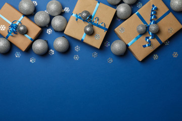 Gift boxes and Christmas balls on blue background, space for text