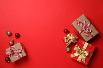 Gift boxes and Christmas baubles on red background, space for text